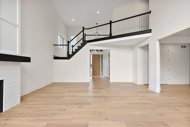 unfurnished living room featuring light hardwood / wood-style flooring and a high ceiling