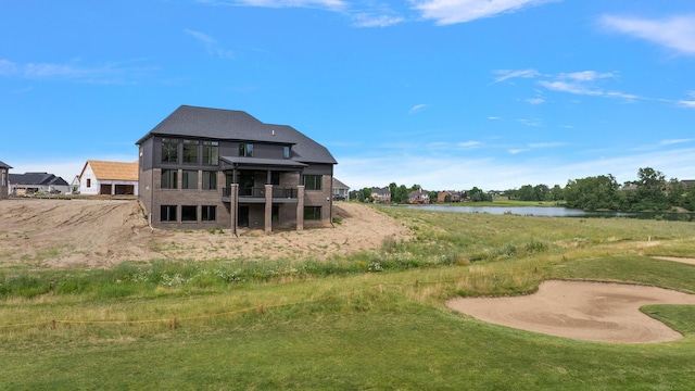 back of house featuring a yard, a water view, and a balcony