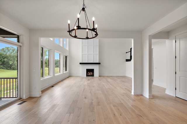 unfurnished living room featuring a fireplace, light hardwood / wood-style flooring, and a notable chandelier