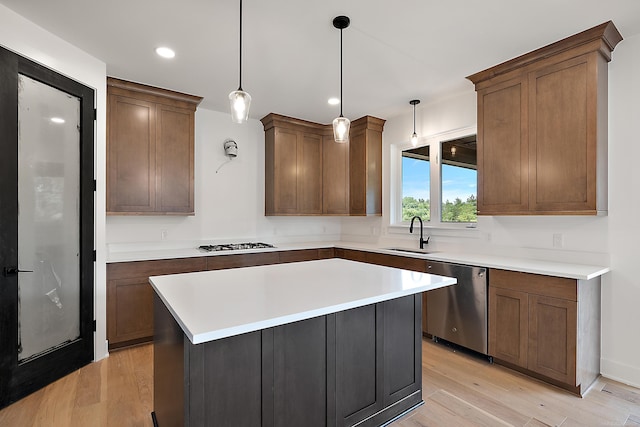 kitchen featuring a center island, light hardwood / wood-style floors, appliances with stainless steel finishes, sink, and decorative light fixtures