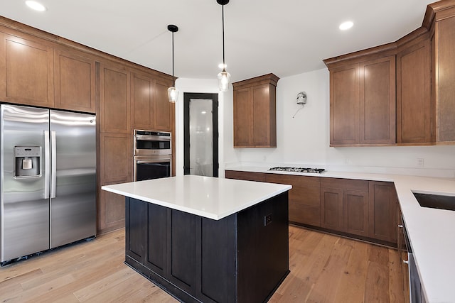 kitchen featuring light hardwood / wood-style floors, a center island, pendant lighting, and appliances with stainless steel finishes