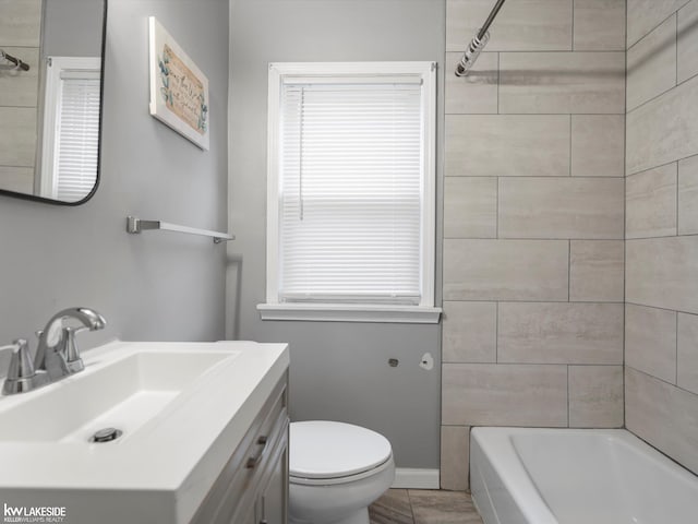 full bathroom with vanity, tiled shower / bath combo, and toilet