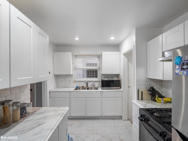 kitchen with backsplash, sink, white cabinets, and appliances with stainless steel finishes