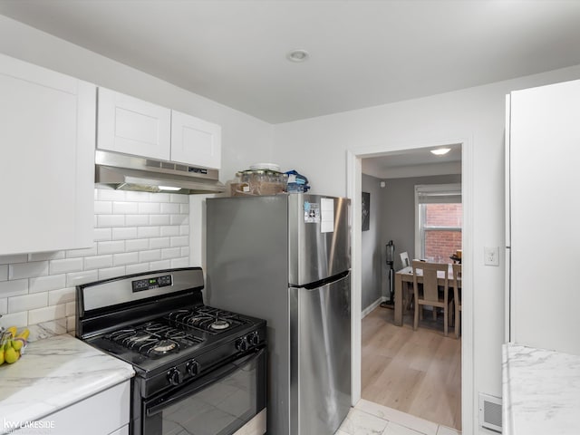 kitchen featuring light stone countertops, backsplash, stainless steel appliances, white cabinets, and light hardwood / wood-style floors