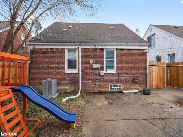 rear view of property featuring a playground and central AC