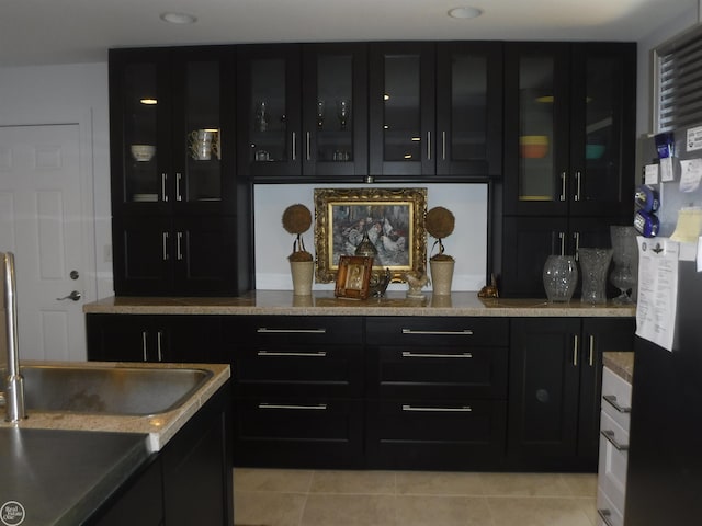 bar featuring black refrigerator, light tile patterned floors, and sink