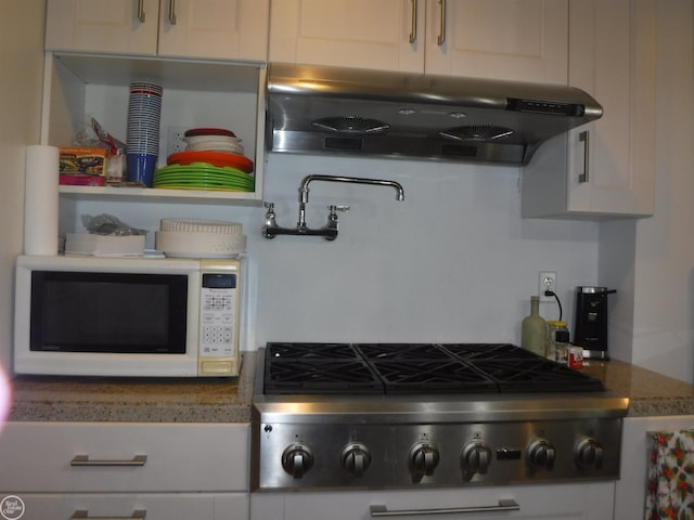 kitchen with ventilation hood, stainless steel gas cooktop, white cabinetry, and stone counters