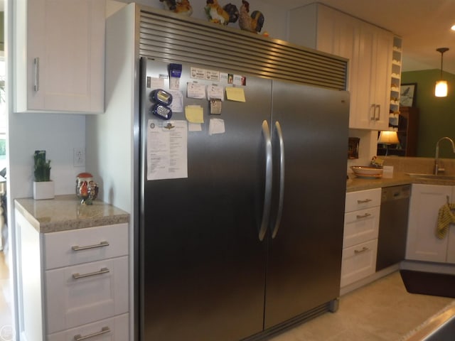 kitchen with sink, white cabinets, stainless steel appliances, and decorative light fixtures