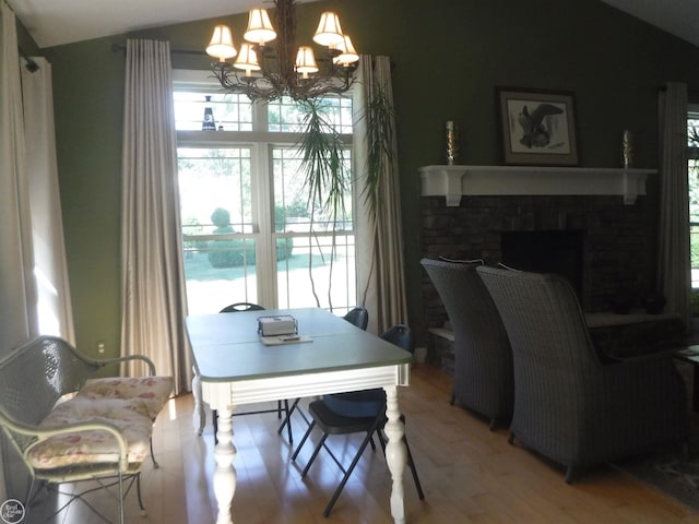 dining space featuring wood-type flooring, a fireplace, and a chandelier