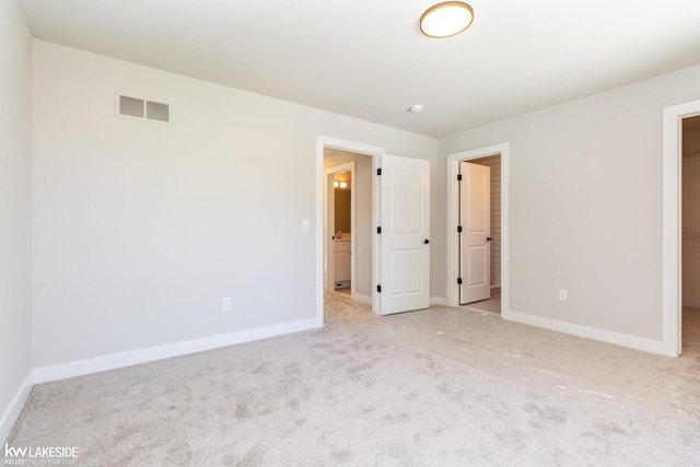 unfurnished bedroom with a walk in closet and light carpet