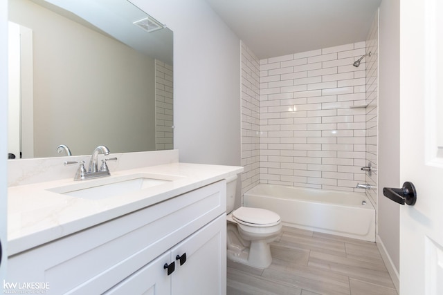 full bathroom with vanity, tiled shower / bath, and toilet