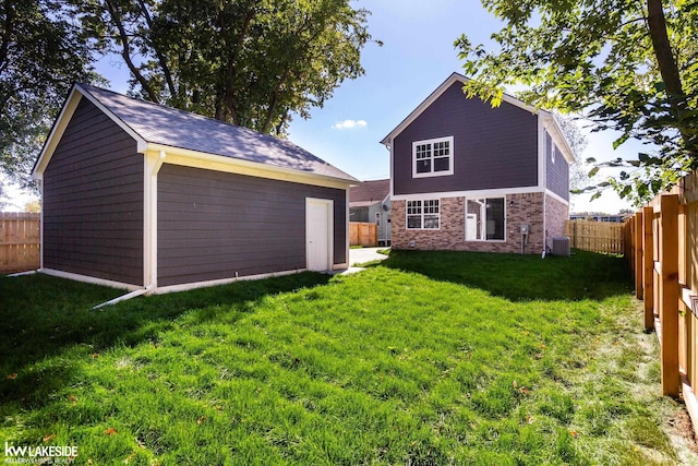 back of house with an outbuilding, a lawn, and central air condition unit