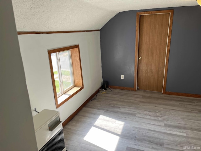 interior space featuring light wood-type flooring, a textured ceiling, and lofted ceiling