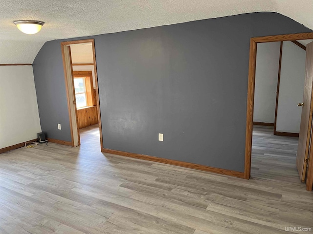 bonus room featuring light hardwood / wood-style floors, a textured ceiling, and vaulted ceiling