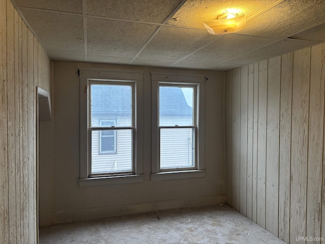 spare room featuring a drop ceiling and wooden walls