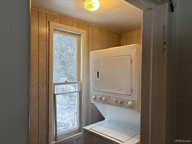 clothes washing area with stacked washer / dryer and wooden walls