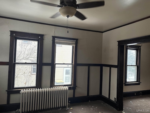 spare room featuring carpet floors, radiator, crown molding, and ceiling fan