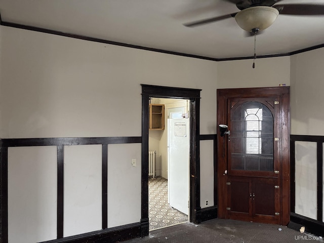 carpeted entrance foyer featuring ceiling fan, ornamental molding, and radiator