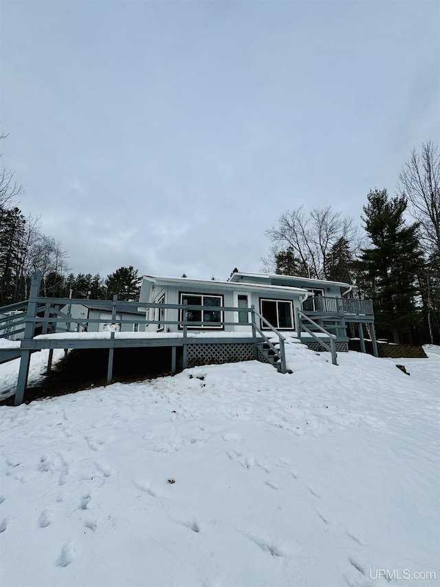 snow covered back of property with a deck