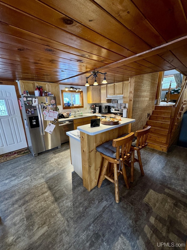 kitchen with stainless steel appliances, a breakfast bar, light brown cabinetry, and wood ceiling