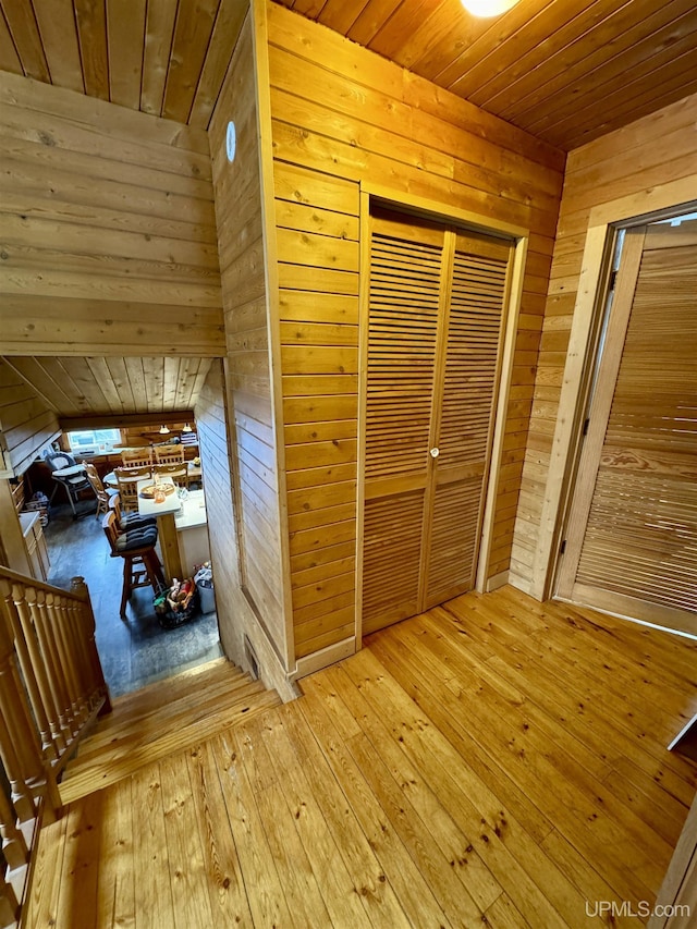 hall featuring wooden walls, wooden ceiling, and wood-type flooring