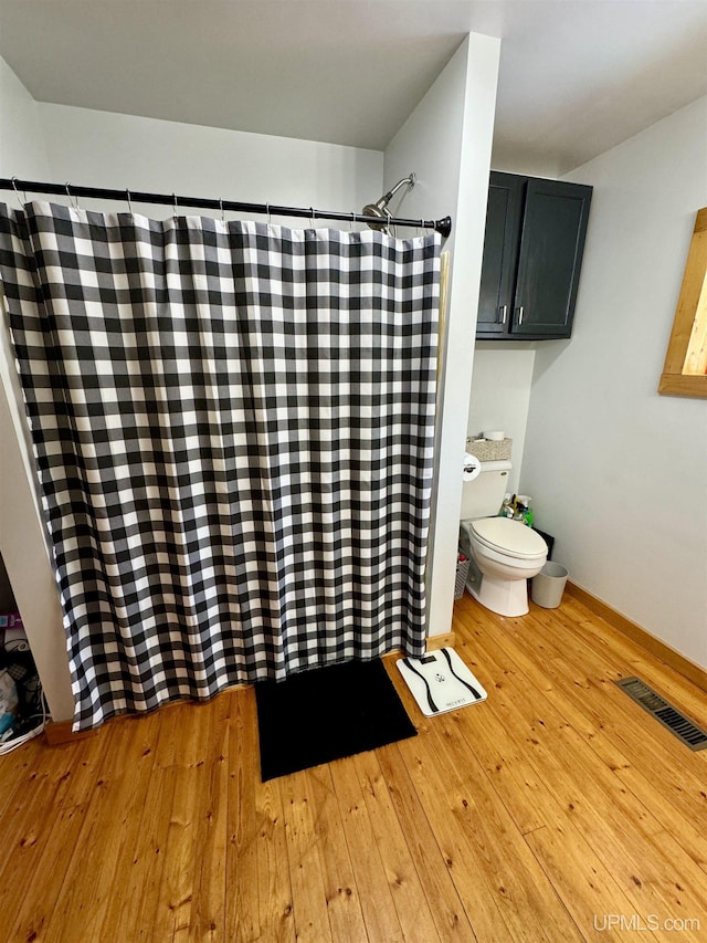 bathroom featuring a shower with curtain, wood-type flooring, and toilet