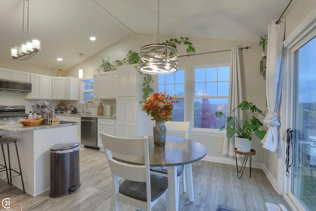 dining space with a notable chandelier, light hardwood / wood-style floors, sink, and vaulted ceiling