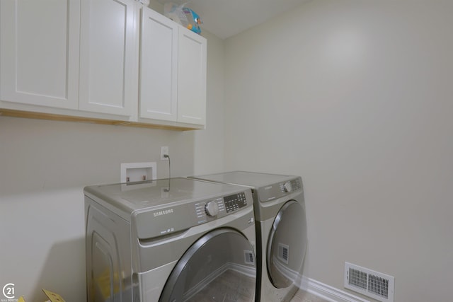 clothes washing area featuring cabinets and washing machine and dryer