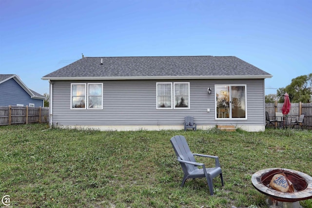 rear view of property with a fire pit and a lawn