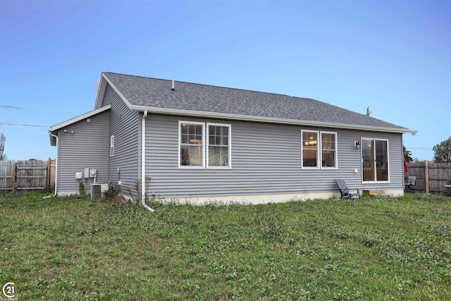 back of property with a yard and central AC