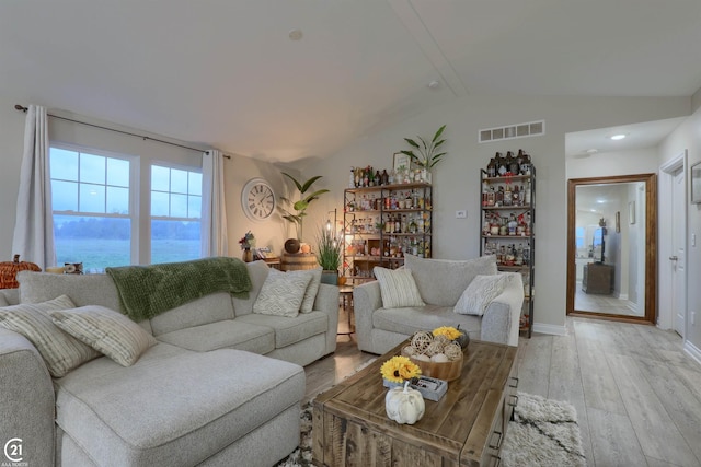 living room with vaulted ceiling with beams, a water view, light wood-type flooring, and indoor bar