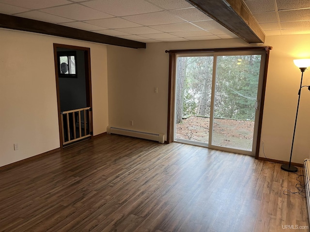 spare room featuring a paneled ceiling, dark hardwood / wood-style flooring, and a baseboard heating unit