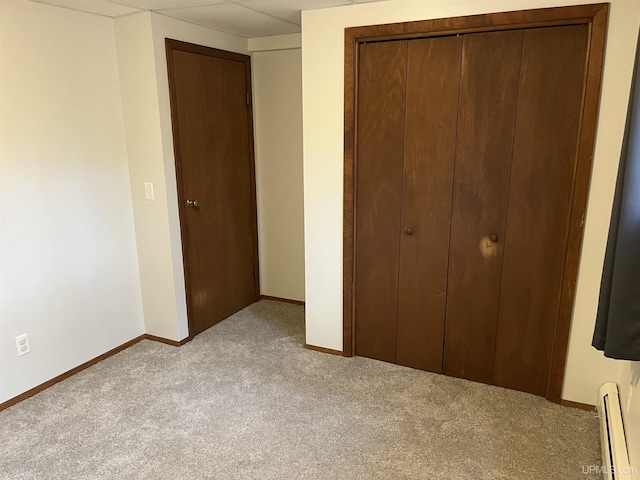 unfurnished bedroom featuring a closet, light colored carpet, and a baseboard radiator