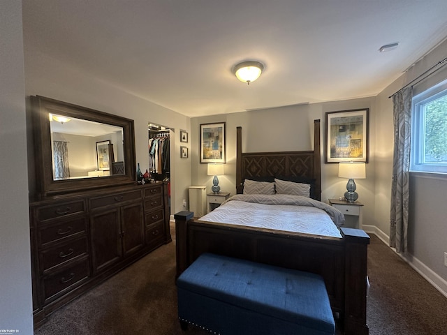 bedroom featuring a spacious closet, a closet, and dark colored carpet