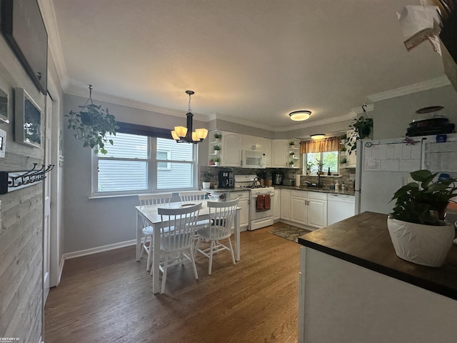 kitchen featuring white appliances, backsplash, white cabinets, decorative light fixtures, and wood-type flooring