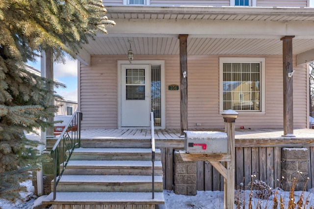 snow covered property entrance featuring covered porch