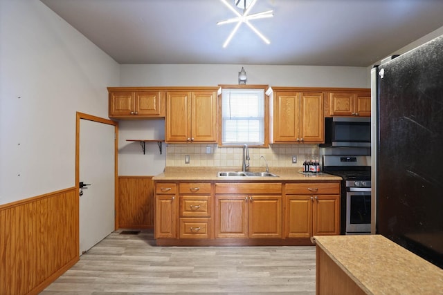 kitchen with decorative backsplash, sink, light wood-type flooring, and appliances with stainless steel finishes