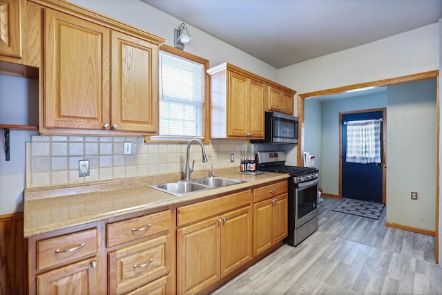 kitchen featuring appliances with stainless steel finishes, tasteful backsplash, light hardwood / wood-style flooring, and sink