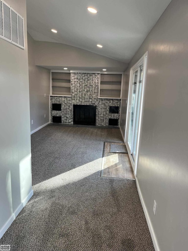 unfurnished living room with built in shelves, a fireplace, carpet floors, and lofted ceiling