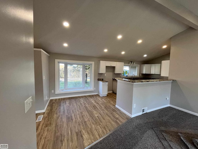 kitchen featuring lofted ceiling, white cabinets, sink, light wood-type flooring, and kitchen peninsula