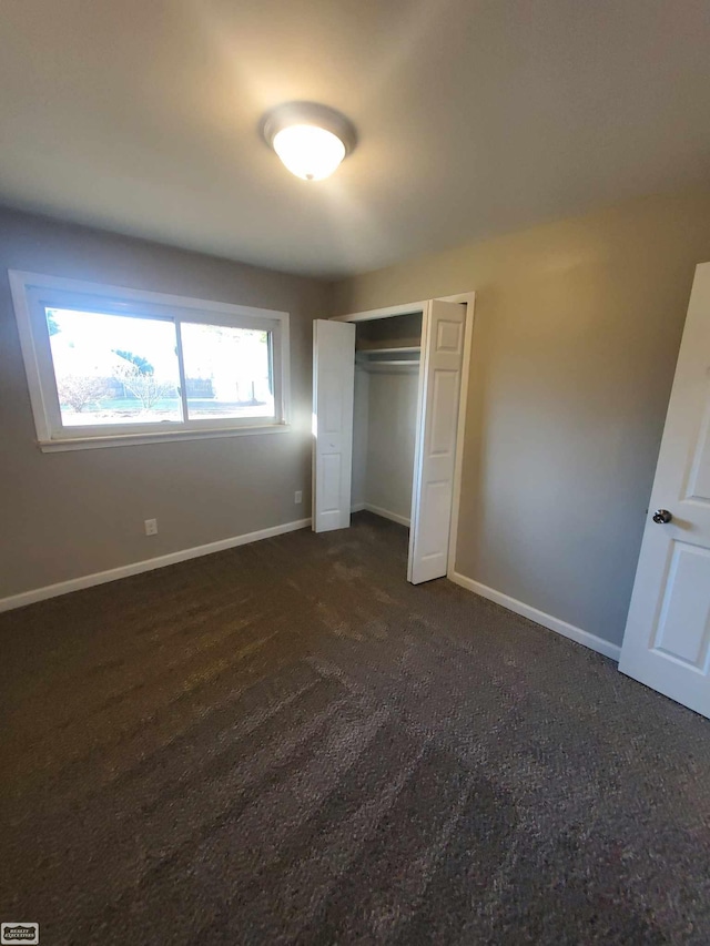 unfurnished bedroom with a closet and dark carpet