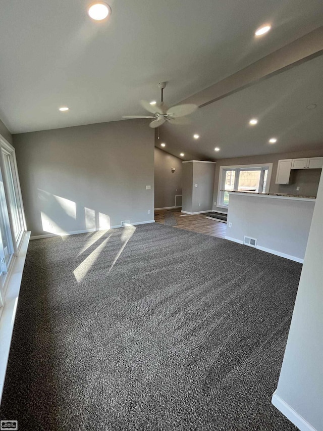 unfurnished living room with dark colored carpet and vaulted ceiling