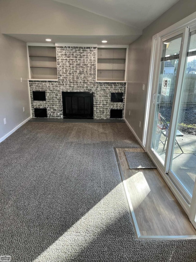 unfurnished living room with built in shelves, carpet floors, and vaulted ceiling