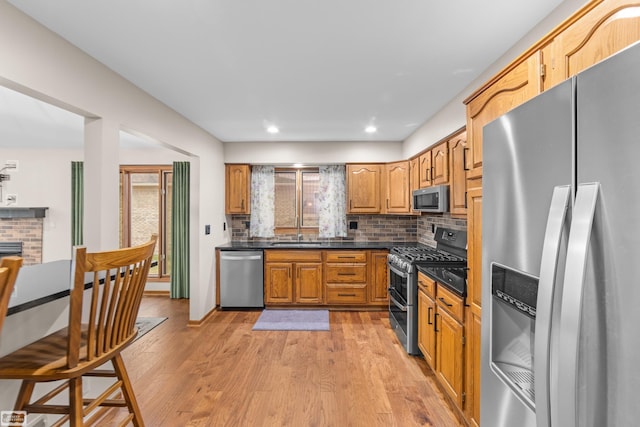 kitchen featuring light wood-type flooring, appliances with stainless steel finishes, backsplash, and sink