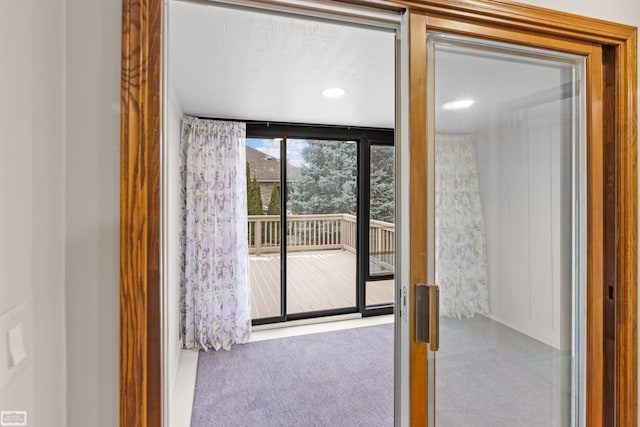 doorway to outside with carpet floors and a wall of windows