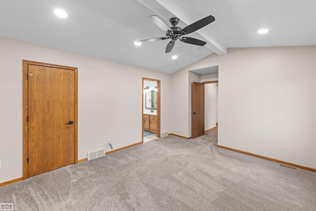 unfurnished bedroom featuring ceiling fan, lofted ceiling with beams, light colored carpet, and ensuite bath