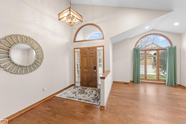 entryway featuring high vaulted ceiling, light hardwood / wood-style floors, and a notable chandelier