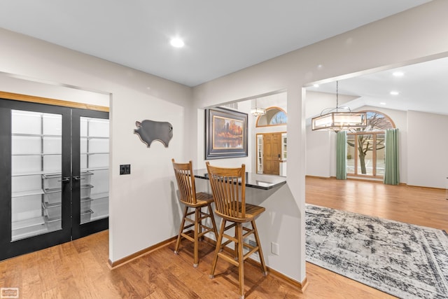 dining area with french doors, a chandelier, vaulted ceiling, and hardwood / wood-style flooring