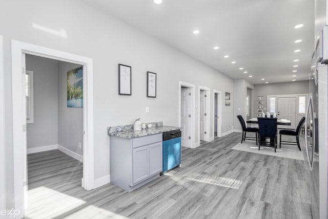 kitchen with white cabinets, light stone countertops, appliances with stainless steel finishes, and light hardwood / wood-style flooring