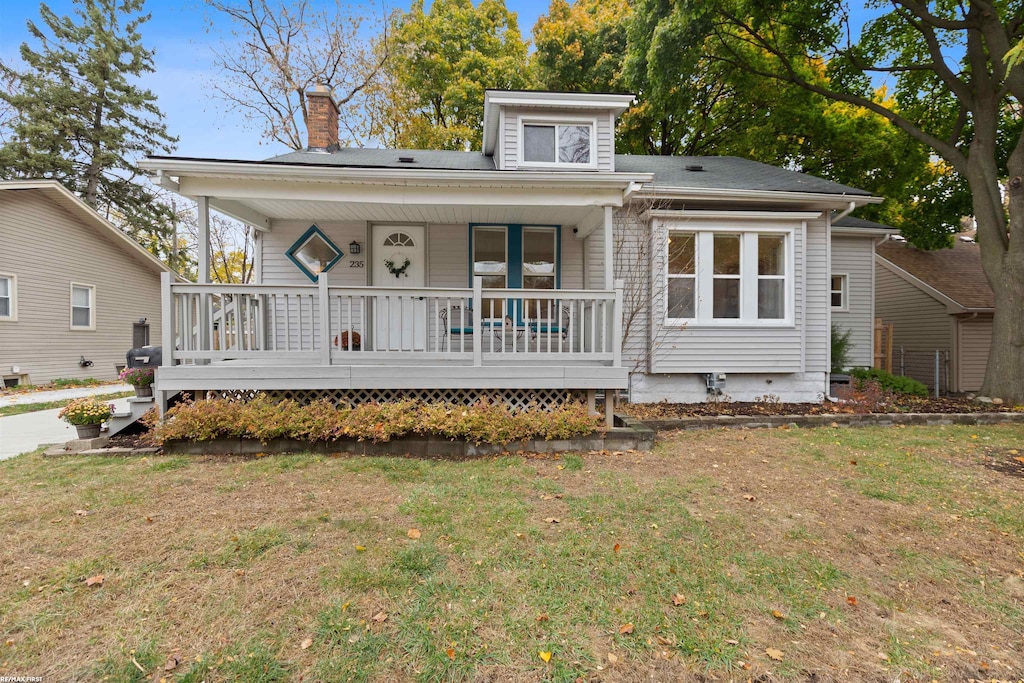 rear view of property featuring covered porch and a yard